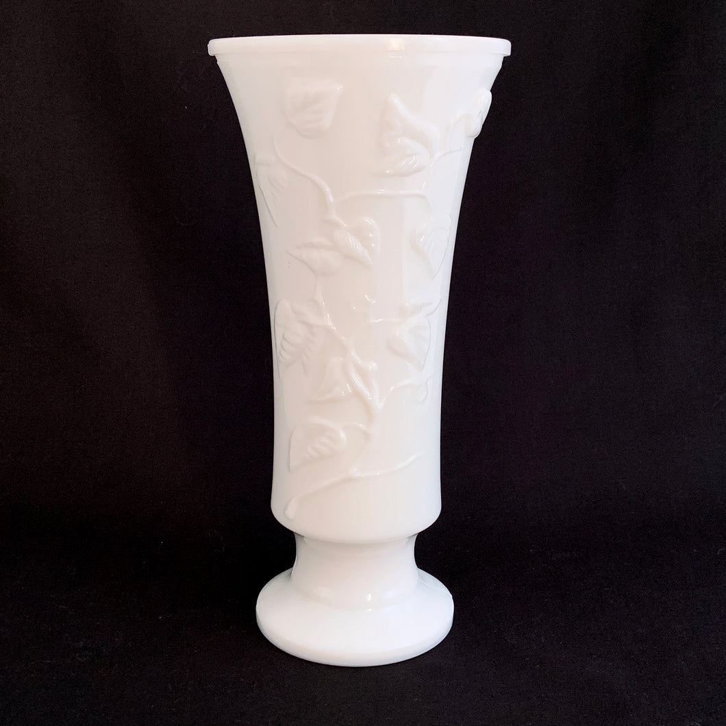 A lovely trumpet shaped footed milk glass vase is embossed with a pattern of intertwining vines.  In excellent condition, no chips or cracks.  Measures 4 1/2 x 9 1/2 inches