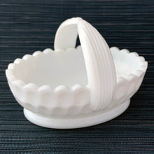 Load image into Gallery viewer, Vintage oval shaped milk glass thumbprint patterned basket with scalloped edge and split handle with ribbed detail. A pretty piece to use for trinkets, candy or as a serving dish. Produced by the Fenton Glass Company as part of their the Olde Virginia Glass line, circa 1970s.  In excellent condition, free from chips/cracks.  Measures 6 1/2 x 4 1/2 x 5 inches
