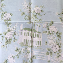 Load image into Gallery viewer, This is a unique textile! Bordered in white this is an absolutely lovely pale aqua blue cotton/linen tablecloth decorated with different white buildings with dark gray or white fences  awash with white roses on gray stems and green leaves. This dreamy table linen will look amazing on any table, or use as a ground cloth for a pretty picnic scene. Easily repurposed as pillows, or a sweet garment.  In excellent condition, free from tears or stains. Circa 1950/60s.  Measures 44 1/2 x 49 1/2 inches
