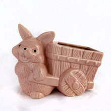 Load image into Gallery viewer, Adorable vintage pink ceramic planter of a bunny rabbit pulling a wagon. Made in Taiwan, circa 1960. Fill this pretty planter with your favourite houseplant or succulents. Could be filled with some delicious confections for a lovely Easter gift or display!  In excellent condition, free from chips/cracks/repairs.  6 1/2 x 3 1/2 x 5 inches
