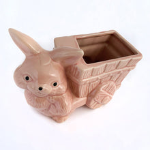 Load image into Gallery viewer, Adorable vintage pink ceramic planter of a bunny rabbit pulling a wagon. Made in Taiwan, circa 1960. Fill this pretty planter with your favourite houseplant or succulents. Could be filled with some delicious confections for a lovely Easter gift or display!  In excellent condition, free from chips/cracks/repairs.  6 1/2 x 3 1/2 x 5 inches
