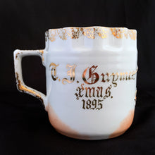Load image into Gallery viewer, Vintage white porcelain shaving mug with slip trail design hand painted in gold, dark pink rose and crimped gold rim and personalized in gold with &quot;T.J. Guymer Xmas 1895&quot;. . Use as intended or repurpose as a toothbrush or make-up brush holder.   In excellent condition, no chips/cracks/repairs. Some wear to the gold. Made in Germany  Dimensions: 3-1/8&quot; x 3-1/4&quot;
