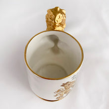 Load image into Gallery viewer, Vintage Staffordshire bone china white miniature souvenir mug made for the coronation of Queen Elizabeth II with the royal crest on one side, date of crowning on the other and a stylized lion handle with gold gilt finish. Produced by Arthur Bowker, England.  In excellent condition, free from chips/cracks/repairs. Marked on the base &quot;STAFFORDSHIRE FINE BONE CHINA OF ARTHUR BOWKER MADE IN ENGLAND&quot;  Measures 2-3/4&quot; x 1-7/8&quot; x 2-3/4&quot;
