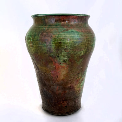 Striking vintage pottery vase in tones of green and copper and fired using the Raku process. Raku is a Japanese method of pottery making dating back to the 1500s. The clay object is removed from the kiln at the height of firing which causes it to cool very quickly causes unusual results and it's signature black clay. This piece is signed on the bottom 