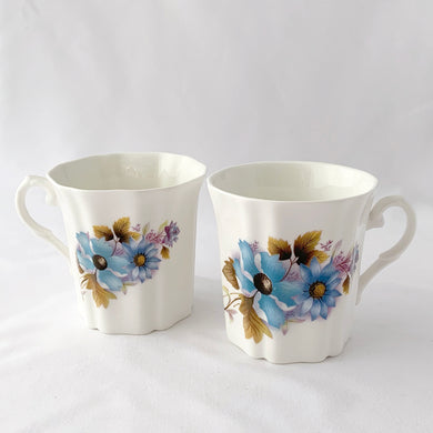 Treat yourself to a cuppa in this lovely feminine shaped fine bone china mug featuring blue and purple flowers with green leaves on white bone china. Crafted by Royal Grafton, England, circa 1970s. Grafton made these mugs with many floral designs — collect them all!  In excellent condition, no chips, cracks or crazing. Marked on the bottom with 