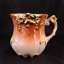 Load image into Gallery viewer, Vintage white porcelain mustache cup with embossed flower details in a deep coral with gold rim and a sweet gold flower on the handle. Use as intended or repurpose as a toothbrush or make-up brush holder.  Made in Germany.  In excellent condition, no chips/cracks/repairs. Some wear to the gold.  Dimensions: 4&quot; x 3-5/8&quot;
