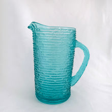 Load image into Gallery viewer, This vintage pressed glass pitcher is perfect for juice, lemonade, ice tea or your favourite beverage. Made in the &quot;Soreno&quot; pattern in luminous aquamarine with a textured bark outer surface. Made by Anchor Hocking between 1966–1970.  In excellent condition, free from chips or cracks.  Measures 7&quot; and holds 1 litre or 1 quart
