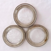 Load image into Gallery viewer, Gorgeous set of three vintage sterling silver rimmed cut crystal coasters. The smooth silver rim features a beaded inner edge and the crystal is cut in a starburst pattern. Elegant and perfect to protect your furniture from condensation marks! Produced by Frank M. Whiting, circa early 20th century, pre-1926.  In good vintage condition with general wear from normal age and use. Marked &quot;Frank M. WHITING &amp; CO STERLING 04 PAT PENDING&quot;.  Each coaster measures 4&quot; x .75&quot;
