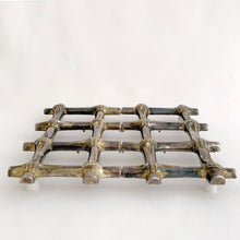 Load image into Gallery viewer, This beautiful vintage Hollywood Regency silver plated bamboo tiki style trivet conveniently extends to accommodate larger dishes and its rubber feet will protect surfaces. Sticker on the bottom reads &quot;Silver Plated Zinc&quot;. Crafted in Hong Kong, circa 1950s. A great way to protect your furniture from getting marked by hot ovenware!  Measures 7 1/4 x 7 1/4 and extends to 10 1/4 inches
