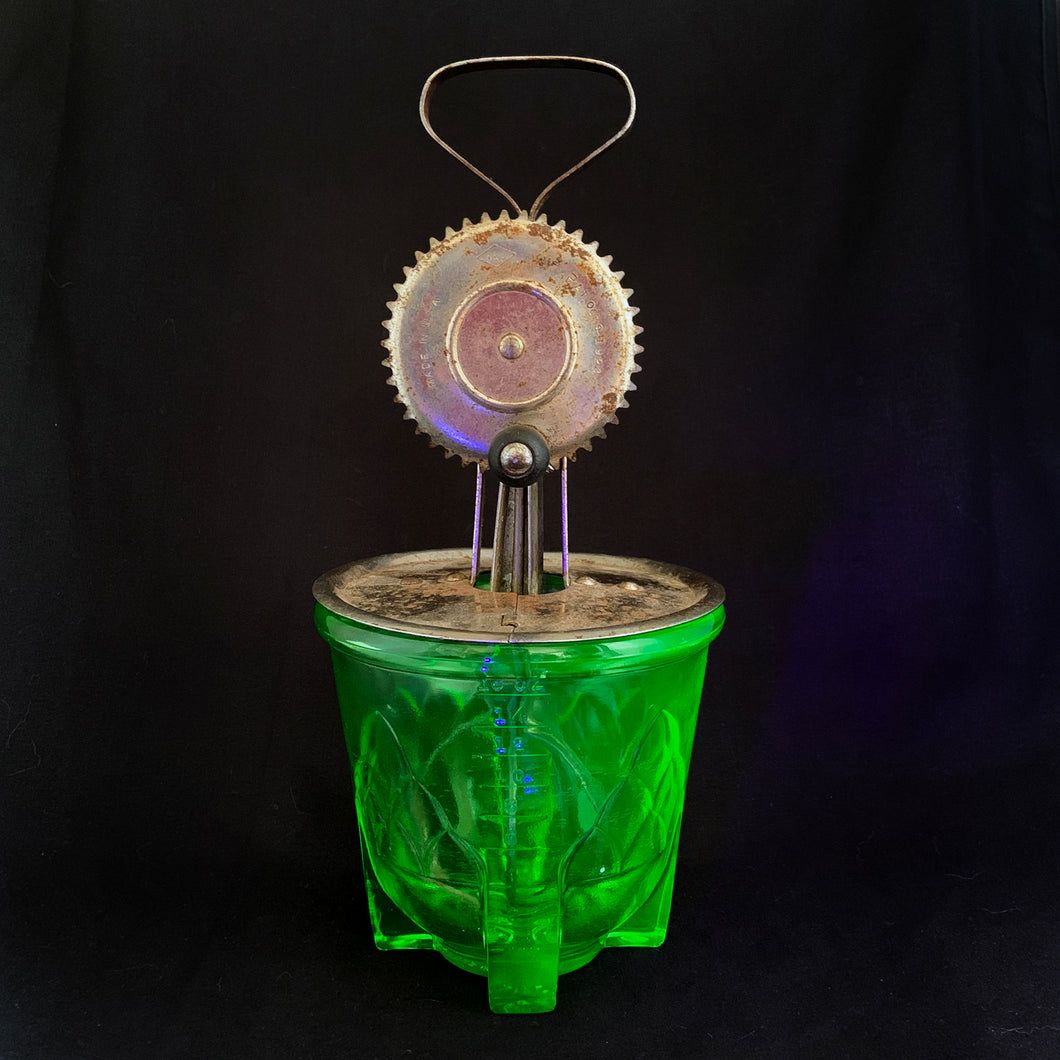 Antique vintage green uranium/vaseline depression era glass footed 2 cup hand beater mixer. The glass cup glows beautifully under black light, has an artichoke design on all 4 sides, measuring lines in 1/4 cup increments and four square feet. Bottom is marked 
