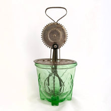 Load image into Gallery viewer, Antique vintage green uranium/vaseline depression era glass footed 2 cup hand beater mixer. The glass cup glows beautifully under black light, has an artichoke design on all 4 sides, measuring lines in 1/4 cup increments and four square feet. Bottom is marked &quot;Patent Applied For&quot;. Produced by Hazel-Atlas Glass, circa 1920.  In overall excellent condition, free from chips/cracks. The metal beater has wear commensurate with age and works well.  Glass measures 4-1/2&quot; x 4-1/4&quot;. Total height with beater is 10&quot;
