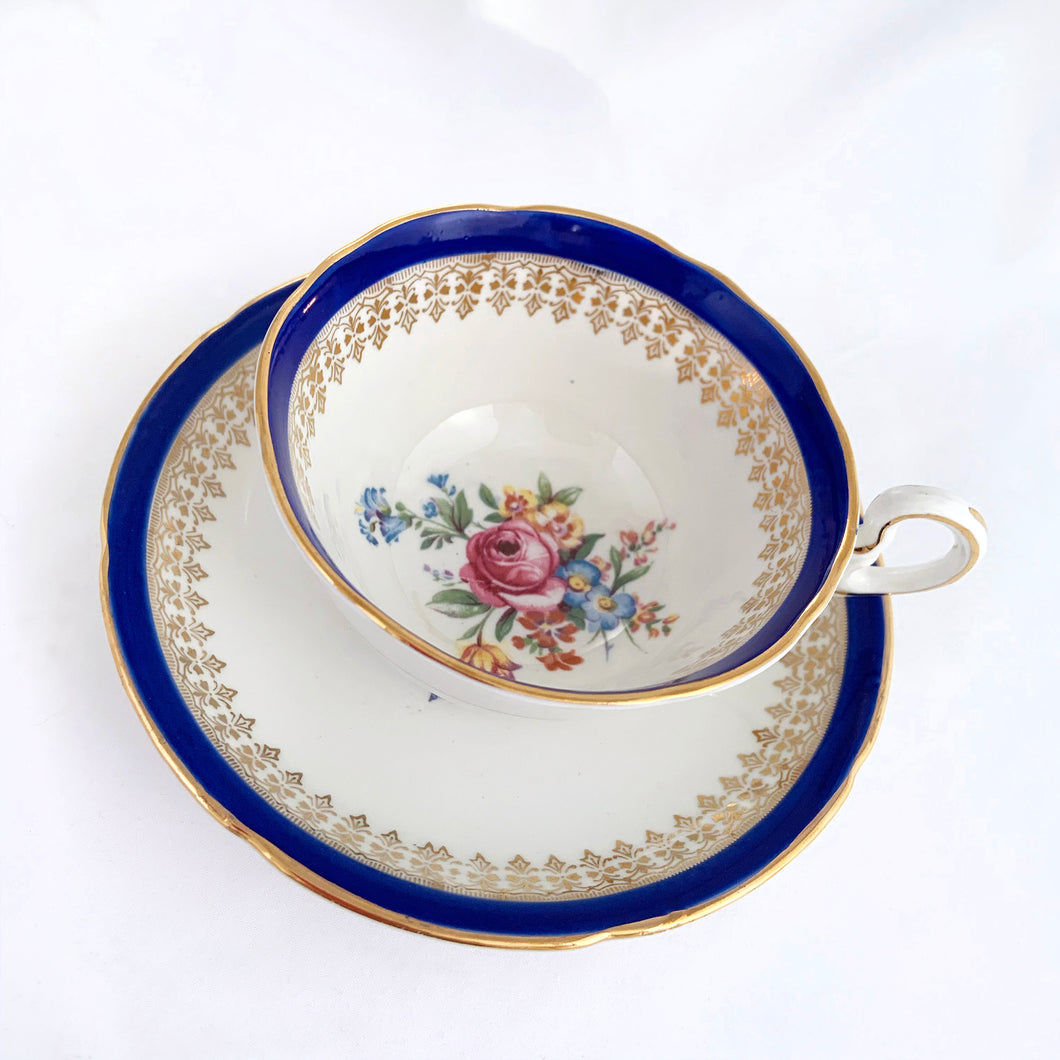 This vintage bone china teacup and saucer is absolutely stunning! Both the cup and saucer are glazed in white with a blue band, gold geometric pattern and rim with a central bouquet of colourful flowers. Produced by Royal Grafton, England, circa 1950 - 1956.  In excellent condition, free from chips, cracks and repairs. Pattern number 1781 marked on the bottom of the teacup.  Teacup measures 3-7/8