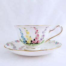 Load image into Gallery viewer, This antique bone china footed teacup and saucer is so sweet! Both the cup and saucer have a lovely scalloped edge with hand painted whimsical pastel coloured foxglove flowers and rimmed with gold gilt. Produced by Royal Albert, England, circa 1917 - 1927. In good condition.  Teacup measures 3 3/4 x 2 3/8 inches  | Saucer measures 5 1/2 inches

