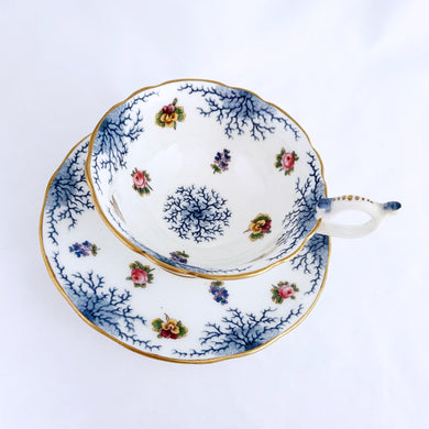 Antique bone china teacup and saucer with scalloped edge and decorated with hand painted pansies and roses with a blue graphic plant and rimmed with gold gilt. Produced by Coalport, England, circa 1900. In good condition, free from chips, cracks and repairs. Manufacturer's defect to the right of the handle at the rim. Pattern number 8252 and maker's marks are on the bottom of the teacup and maker's mark on the saucer. Teacup measures 4