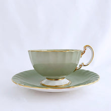 Load image into Gallery viewer, vintage bone china teacup and saucer with a lovely scalloped shape. The cup is a lovely shade of celadon green, interior celadon band is overlaid with a complex gold pattern with a central bouquet of colourful flowers. Saucer is celadon green with a white centre and gold gilt rim. Produced by Aynsley, England, circa 1939. In excellent condition, free from chips, cracks and repairs. Pattern number C1557 with maker&#39;s marks. Teacup measures 3-1/2&quot; x 2-1/4&quot;  | Saucer measures 5-5/8&quot;
