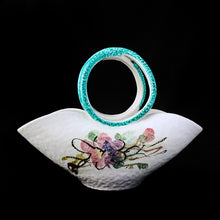 Load image into Gallery viewer, This vintage mid-century hand crafted folded white ceramic pottery basket, features a matte white glaze hand painted with colourful flowers and topped with a uniquely shaped turquoise folded infinity handle. The pottery has a slight texture which adds to its charm. Made in Italy. It&#39;s just that gorgeous!  In excellent condition, free from chips/cracks/repairs. Marked on the bottom with &quot;671/159 Italy&quot;  Measures 8 7/8 x 4 3/4 x 6 1/2 inches   
