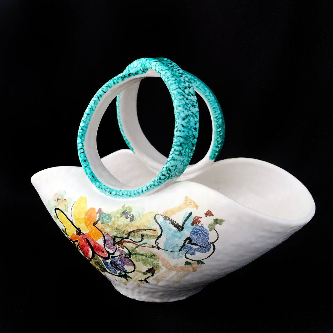 This vintage mid-century hand crafted folded white ceramic pottery basket, features a matte white glaze hand painted with colourful flowers and topped with a uniquely shaped turquoise folded infinity handle. The pottery has a slight texture which adds to its charm. Made in Italy. It's just that gorgeous!  In excellent condition, free from chips/cracks/repairs. Marked on the bottom with 