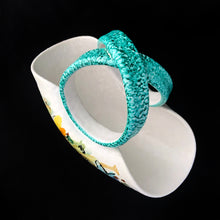 Load image into Gallery viewer, This vintage mid-century hand crafted folded white ceramic pottery basket, features a matte white glaze hand painted with colourful flowers and topped with a uniquely shaped turquoise folded infinity handle. The pottery has a slight texture which adds to its charm. Made in Italy. It&#39;s just that gorgeous!  In excellent condition, free from chips/cracks/repairs. Marked on the bottom with &quot;671/159 Italy&quot;  Measures 8 7/8 x 4 3/4 x 6 1/2 inches   
