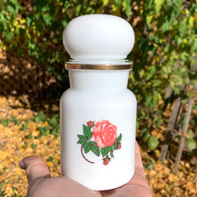 Load image into Gallery viewer, This vintage 1970s white milk glass apothecary jar, with a bubble-shaped lid is a classic piece of vintage glass decorated with pink roses and gold trim. Could be used as a kitchen canister, bathroom apothecary jar or as a beautiful display piece. It has a plastic piece that makes a great seal if using for food storage. Marked on the bottom &quot;Container Made in Belgium&quot;. Circa 1970s/1980s.  In excellent condition, no chips or cracks.  Measures 2-1/8&quot; x 5-1/2&quot;
