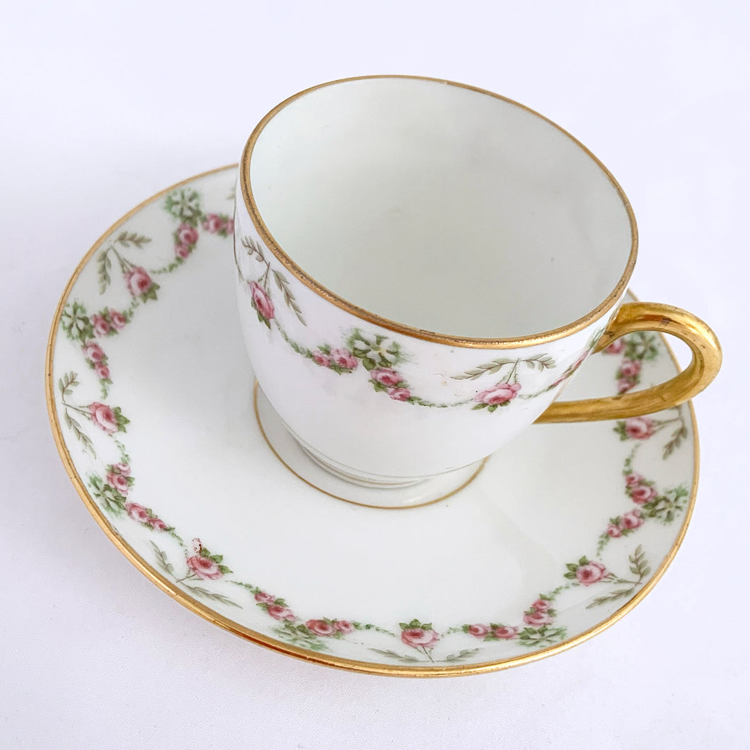 Pretty white porcelain demitasse cup and saucer hand painted with pink and green floral swags with gold trim. Produced by L. Bernardaud & Co., Limoges, France for Birks.  Tiniest of flea nicks on one cup. Remaining pieces are in excellent condition, free from chips/cracks/repairs.  Dimensions of cups 2-3/8