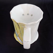 Load image into Gallery viewer, This vintage white porcelain shaving scuttle mug is hand painted with windmill and barn scene inside a gold triangle surrounded with yellow. The mug has raised art nouveau details. Use as intended or repurpose as a toothbrush or make-up brush holder.  Marked &quot;Made in Germany&quot; with an embossed multi-pointed sun.  In excellent condition, no chips/cracks/repairs. Some wear to the gold.  Measures 4 3/4 x 3 3/4 inches
