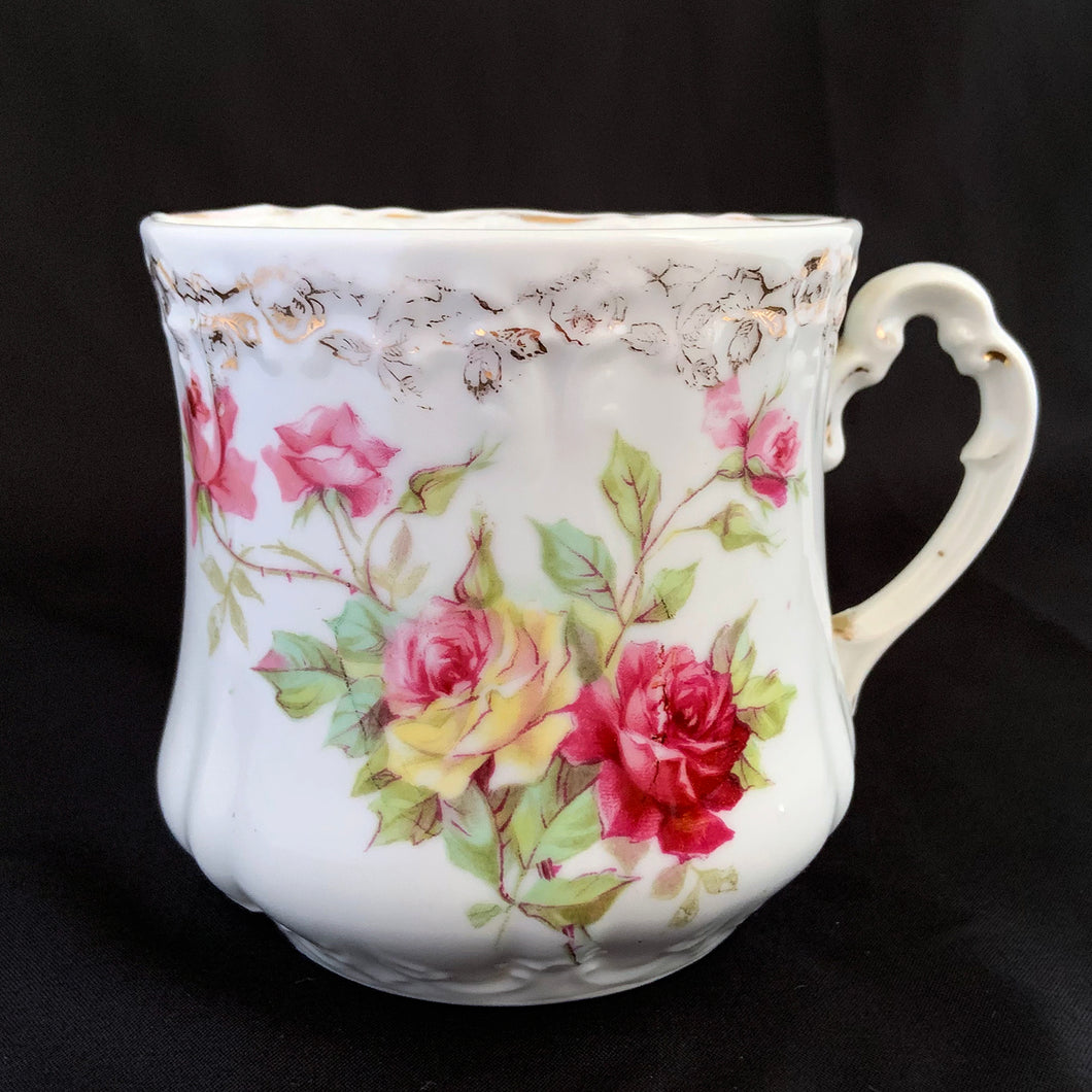 Vintage white porcelain shaving mug with pink and yellow roses with pink and gold around the rim and handle. Use as intended or repurpose as a toothbrush, make-up brush holder.  Maker unknown. Likely German made.  In excellent condition, no chips/cracks/repairs. Some wear to the gold.  Dimensions: 3-1/2