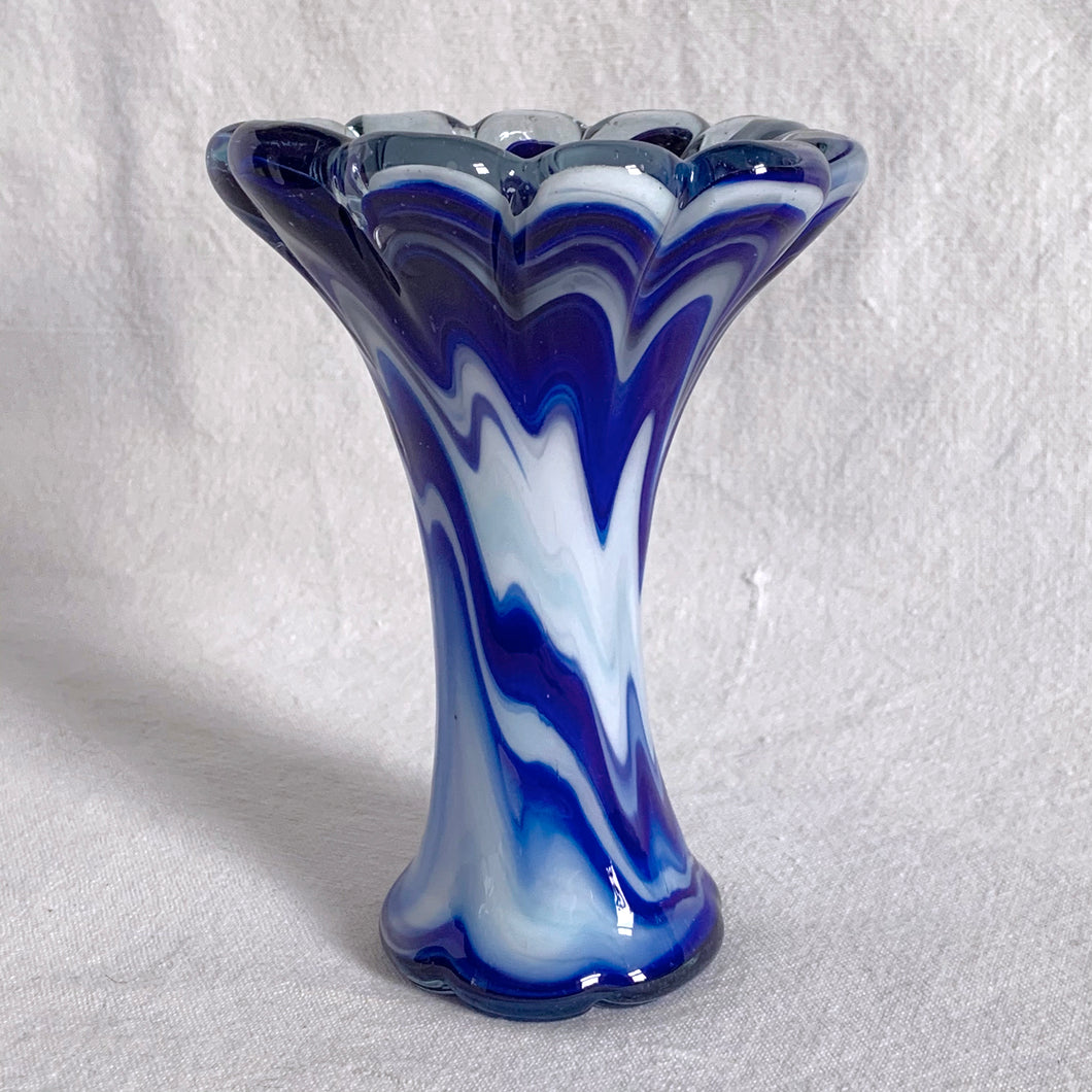 This gorgeous vintage cased glass vase encapsulates blue and white glass in a clear overcoat. The swirl pattern is beautiful, the colours are rich and the trumpet shape reveals a scalloped flower edge. A unique, one-of-a-kind piece.  In excellent condition, no chips or cracks.  Measures 4 x 5 1/2 inches