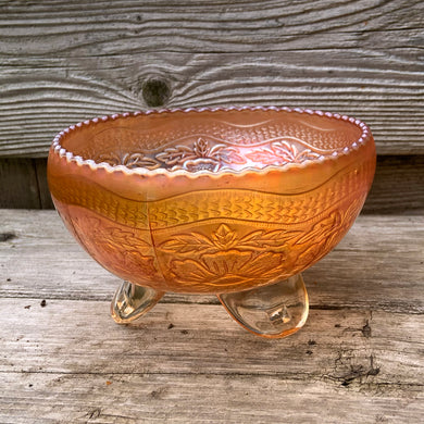 This vintage Two Flowers marigold carnival glass bowl features an intricate design of dogwood flowers and marsh lilies, a smooth sawtooth rim and three spatulate feet. Crafted by Fenton Art Glass, early 20th century. The iridescence on this bowl is outstanding and it's sure to become a treasured heirloom.  In excellent condition, no chips.  Measures 6 1/4 x 3 1/2 inches