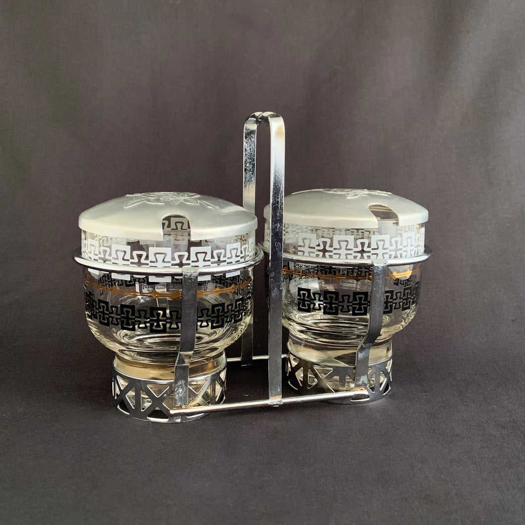 A great mid century glass and aluminum lidded condiment set made by the Libbey Glass Company, USA, circa 1950s. The glass containers each having a black and white design. They fit nicely into their metal caddy with aluminum lids decorated with pinecones that fit atop each glass jar.  The set is in excellent condition.  The caddy measures about 6 1/2 inches in length and 5 1/8 inches in height. 