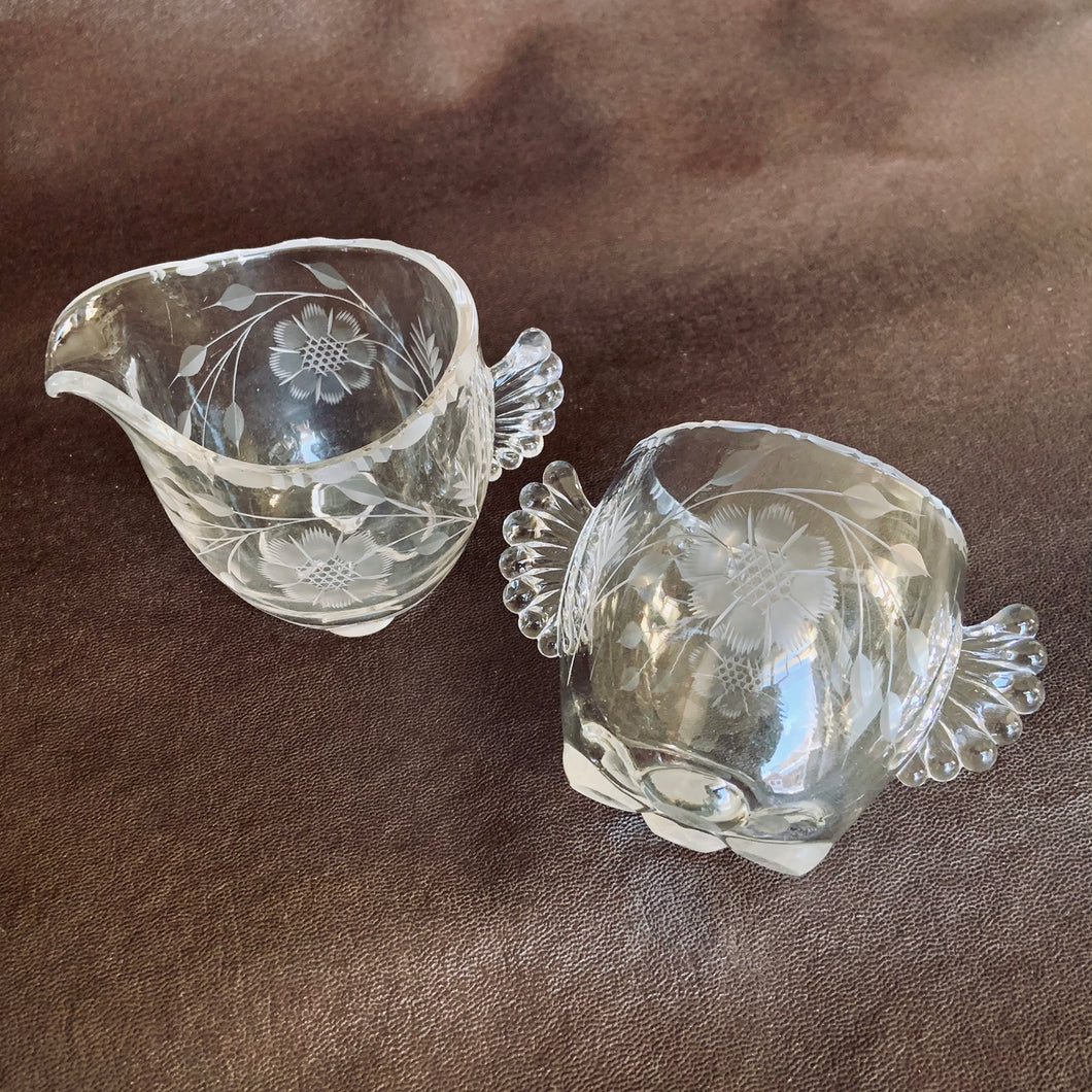 Elegant vintage glass creamer and sugar set cut Gazebo shape, featuring two sets of 8-petalled flowers and leaf sprays, with hand blown glass handles that look like wings, plus a beaded edge and cute little bun feet. Crafted by on Paden City Glass Company, USA, circa 1940s. A unique set to grace your table!  In excellent condition, no chips or cracks.  Shape #555  Measures 3 inches 