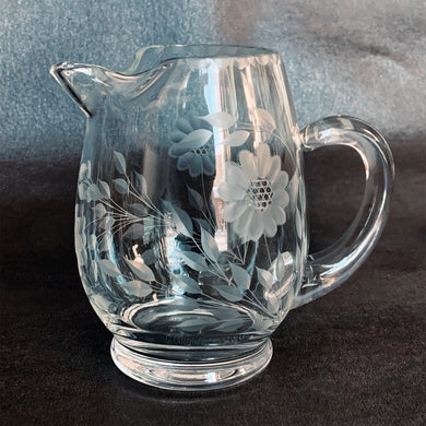 Elegant vintage cut Corn Flower clear glass ice lip pitcher with 3 sets of 12-petalled corn flowers and leaf sprays, beaded rim with applied blown glass open handle. Crafted by WJ Hughes, Canada. This locally cut mini-jug is an important part of Toronto's rich history of fine mid-20th century craftsmanship. A hard-to-come-by piece.

In excellent condition, free from chips/cracks.

Measures 6 inches tall