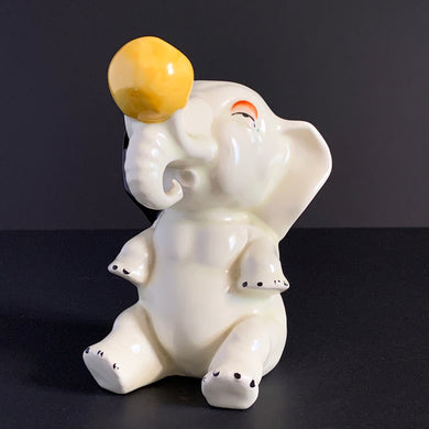 Adorable art deco style ceramic figurine of a white Circus Elephant balancing a vibrant  yellow ball on his trunk. Crafted by Crown Devon, England, circa 1920s/30s. A sweet piece to add to your elephant collection or add whimsy to a child's room. The ceramic figurine is in excellent overall condition free from chips/cracks/repairs. Minor paint loss...see pics. Marked 