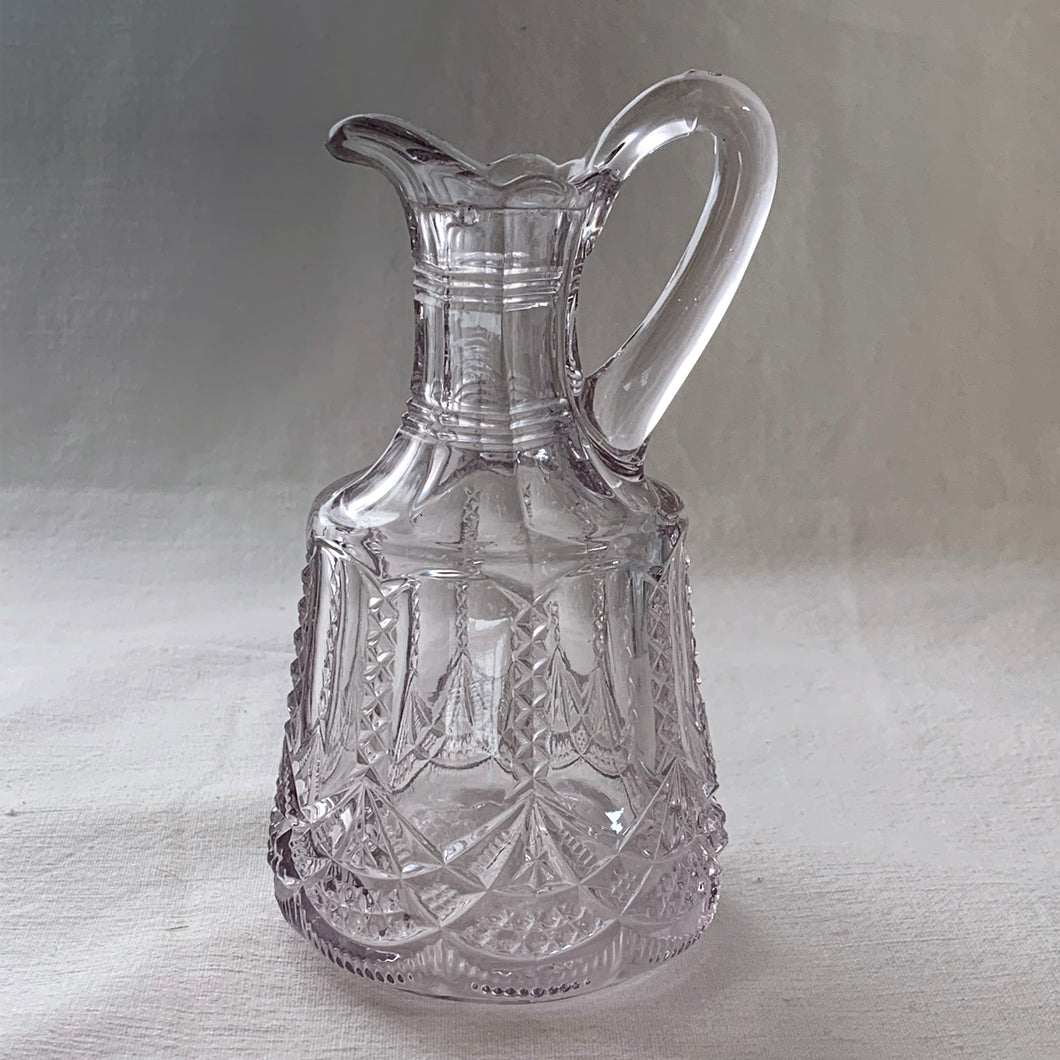 This lovely little glass vinegar cruet. Crafted by Flint Glass, USA, circa early 19th century. The glass has a violet tinge due to the manganese content in the glass which when exposed to sunlight has a tendency to turn violet in colour. A pretty piece!  In excellent used condition. There is a tiny chip on the inside where the stopper was placed.  Approximately 5 inches tall   