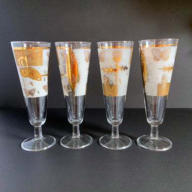 These vibrant vintage mid-century clear pilsner or champagne glasses feature a delightful pattern of 22kt gold butterflies, thistles and botanicals on a frosted band. Designed by Fred Press, USA, circa 1960s. A stunning addition to your luxury barware collection!

In excellent condition, free from chips. Minor wear commensurate with age.

Measures 8 1/2 inches tall