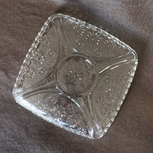 Load image into Gallery viewer, Sweet vintage clear pressed glass relish dish with embossed flowers and a sawtooth edge. Produced by the Hazel-Atlas Glass Company, circa 1950s. Perfect for candies, pre-dinner pickles or use as a trinket tray in your boudoir or bath.  In excellent condition, no chips or cracks.  Size: 6.25” x 6.25” x 1”
